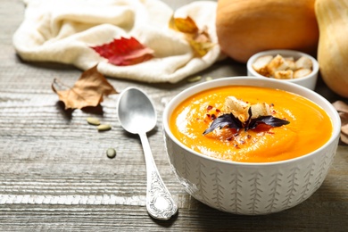 Photo of Delicious pumpkin soup in bowl on wooden table