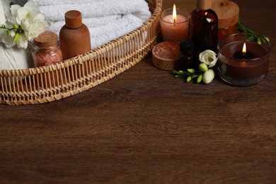 Photo of Beautiful composition with different spa products and burning candles on wooden table. Space for text