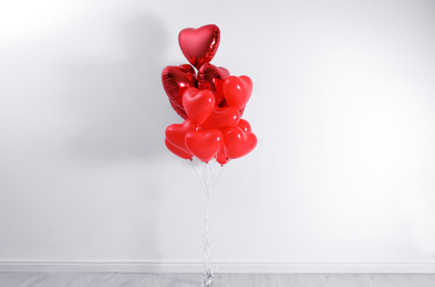 Photo of Bunch of heart shaped balloons near white wall. Valentine's day celebration