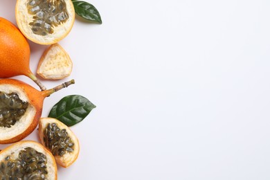 Photo of Delicious ripe granadillas with leaves on white background, flat lay. Space for text