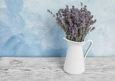 Photo of Pitcher with blooming lavender flowers on table