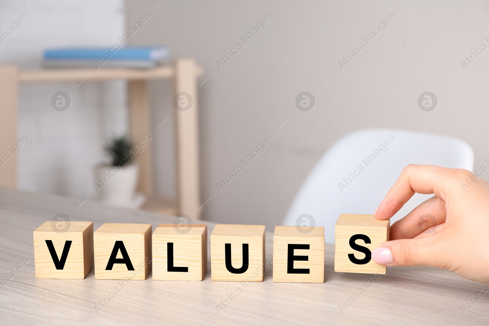 Photo of Woman putting cubes with word VALUES on wooden table, closeup