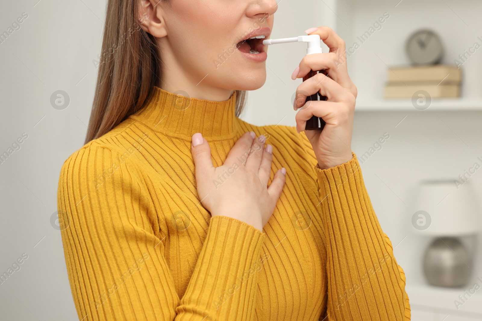 Photo of Adult woman using throat spray at home, closeup