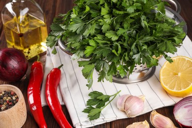 Photo of Colander with fresh parsley, spices and other products on wooden table