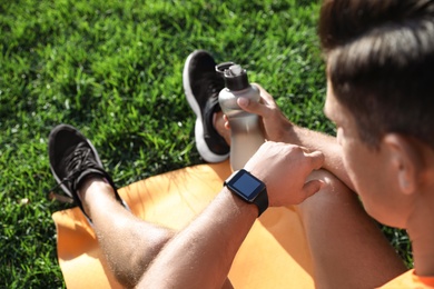 Photo of Man checking fitness tracker after training in park, closeup