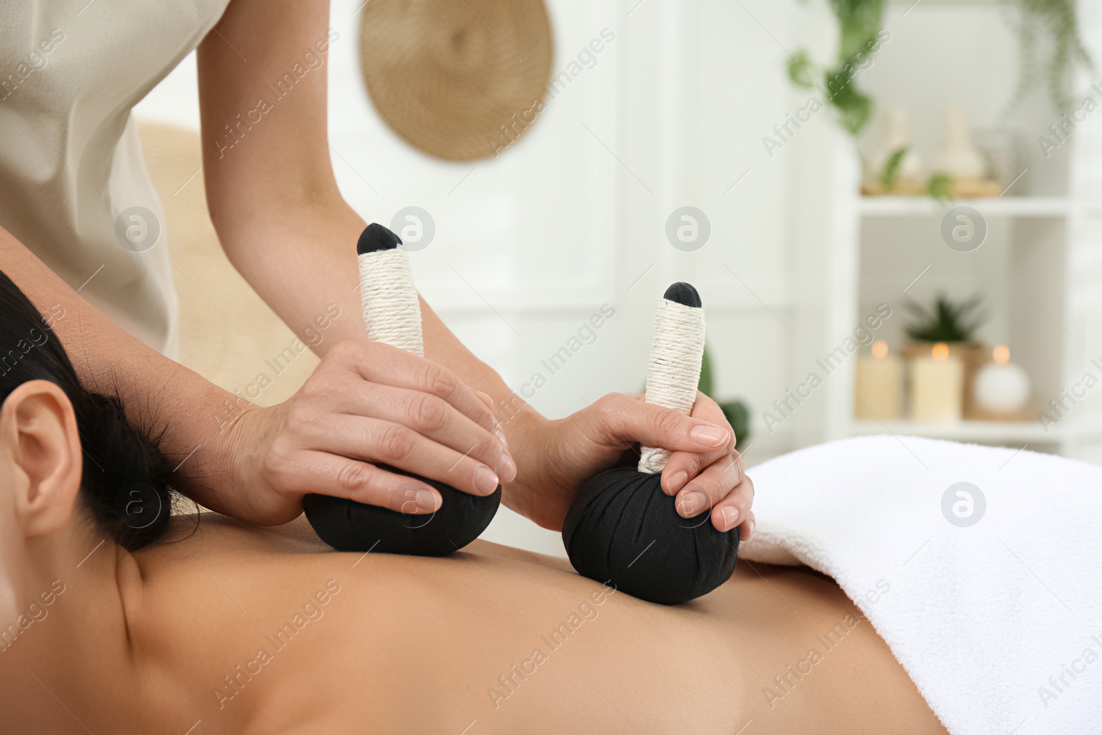 Photo of Young woman receiving herbal bag massage in spa salon, closeup