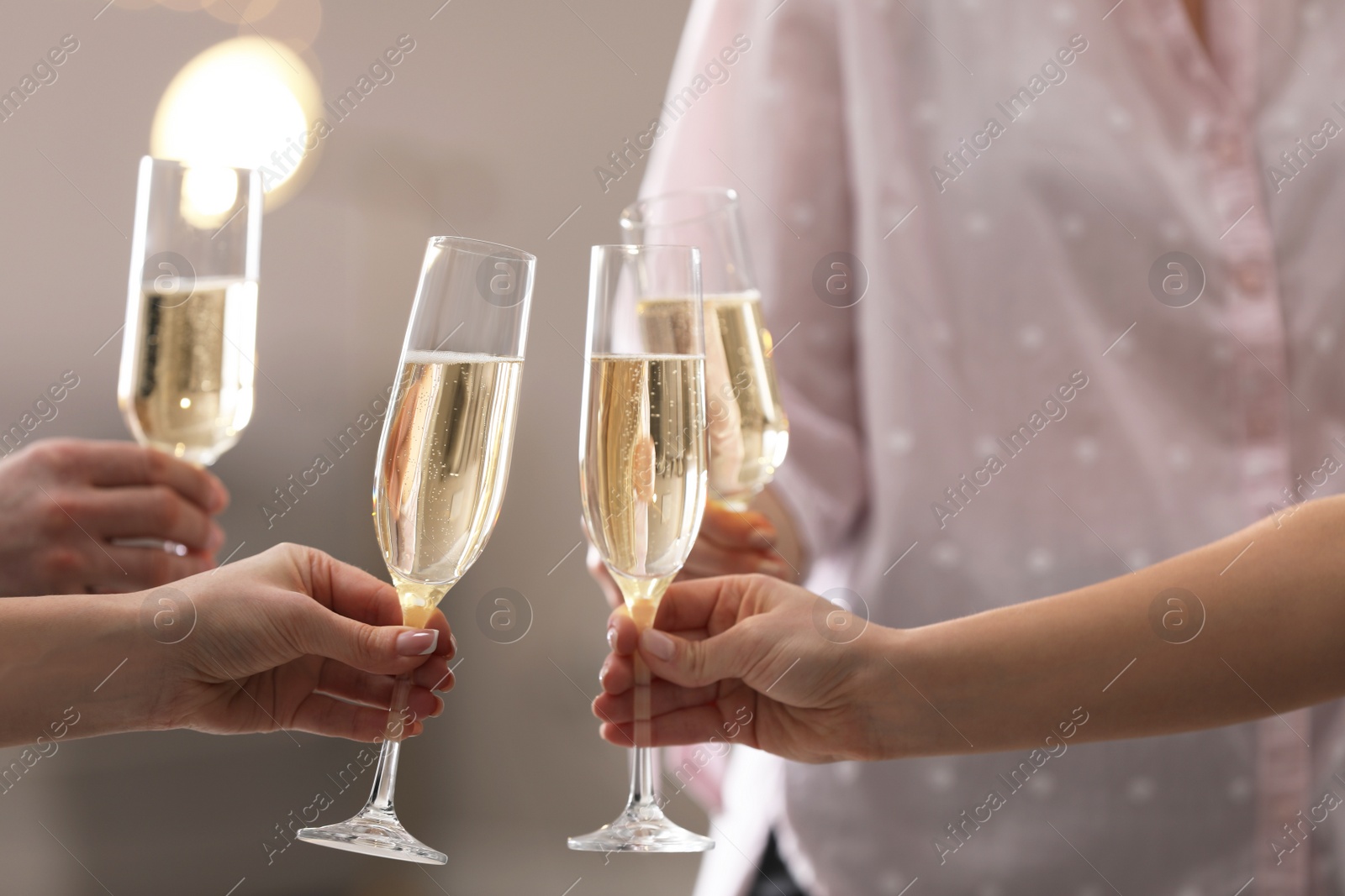 Photo of People clinking glasses of champagne against blurred background, closeup