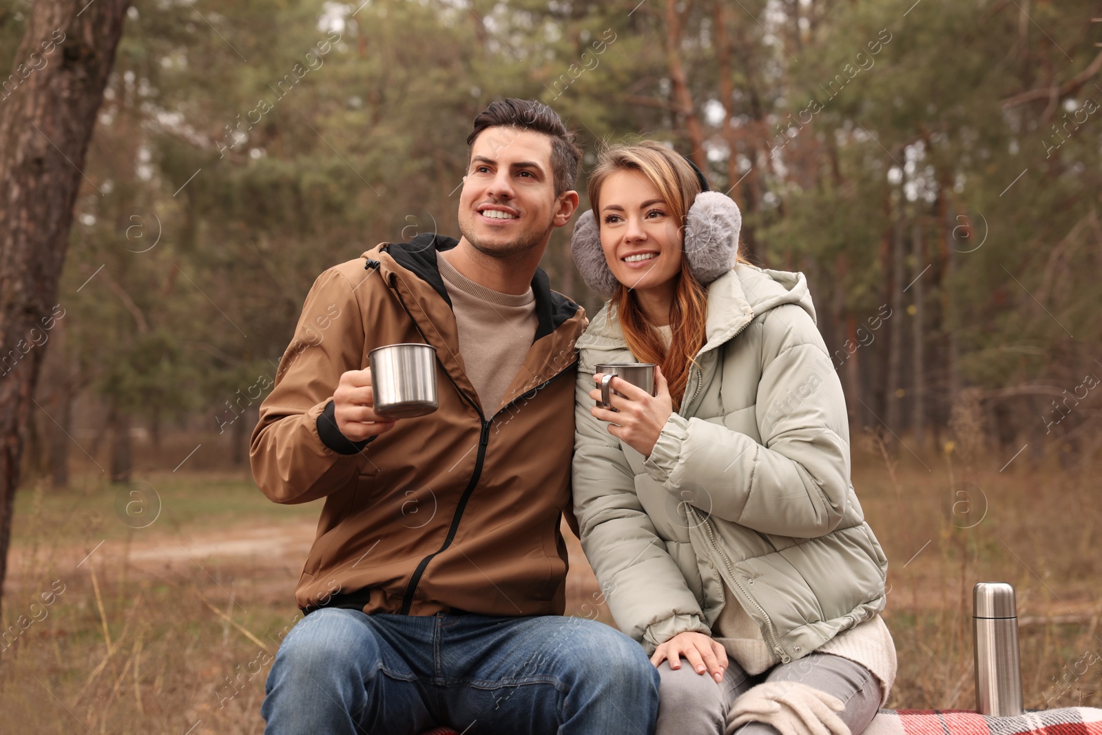 Photo of Happy couple with hot drinks spending time together in forest