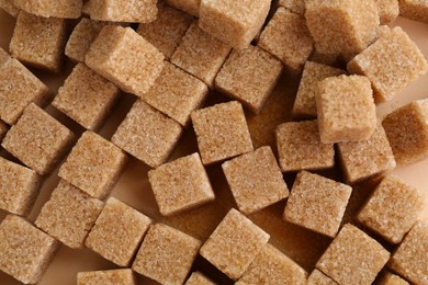 Photo of Brown sugar cubes on color background, top view