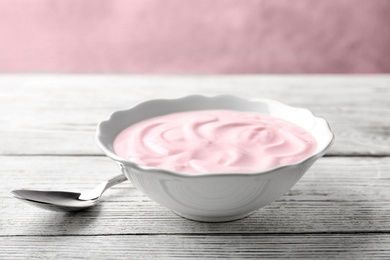 Bowl with tasty yogurt on wooden table