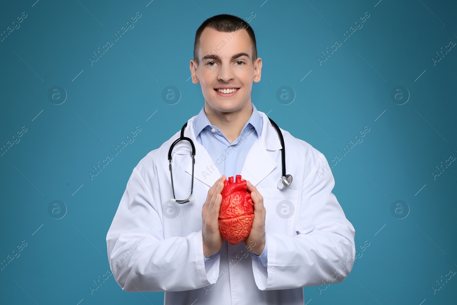 Photo of Young man in white coat with heart model on color model