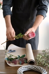 Male florist creating beautiful bouquet at table, closeup