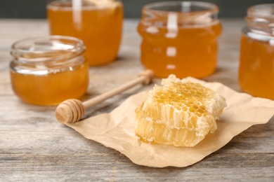 Photo of Honeycomb, dipper and jars on table, closeup