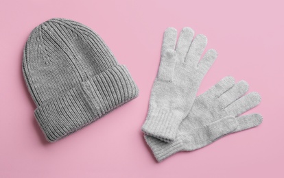 Woolen gloves and hat on pink background, flat lay