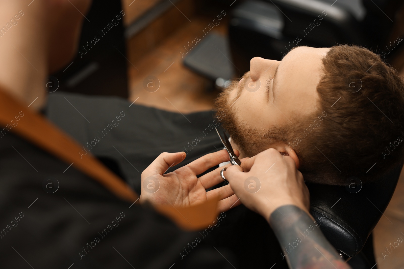 Photo of Professional hairdresser working with bearded client in barbershop