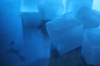 Crystal clear ice cubes on light blue background, closeup with space for text. Color tone effect