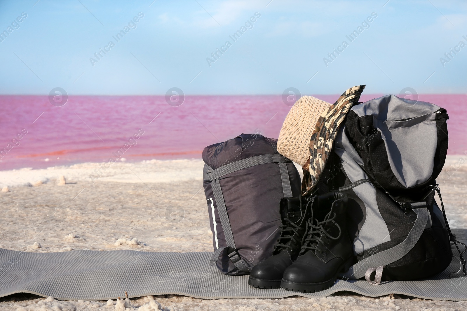 Photo of Set of camping equipment with sleeping bag on coast of pink lake