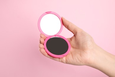 Photo of Woman holding stylish cosmetic pocket mirror on pink background, closeup