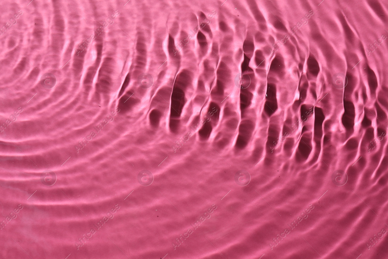 Photo of Rippled surface of clear water on bright pink background, top view