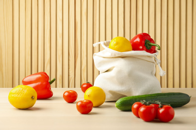 Photo of Cotton eco bag with vegetables and fruits on wooden table