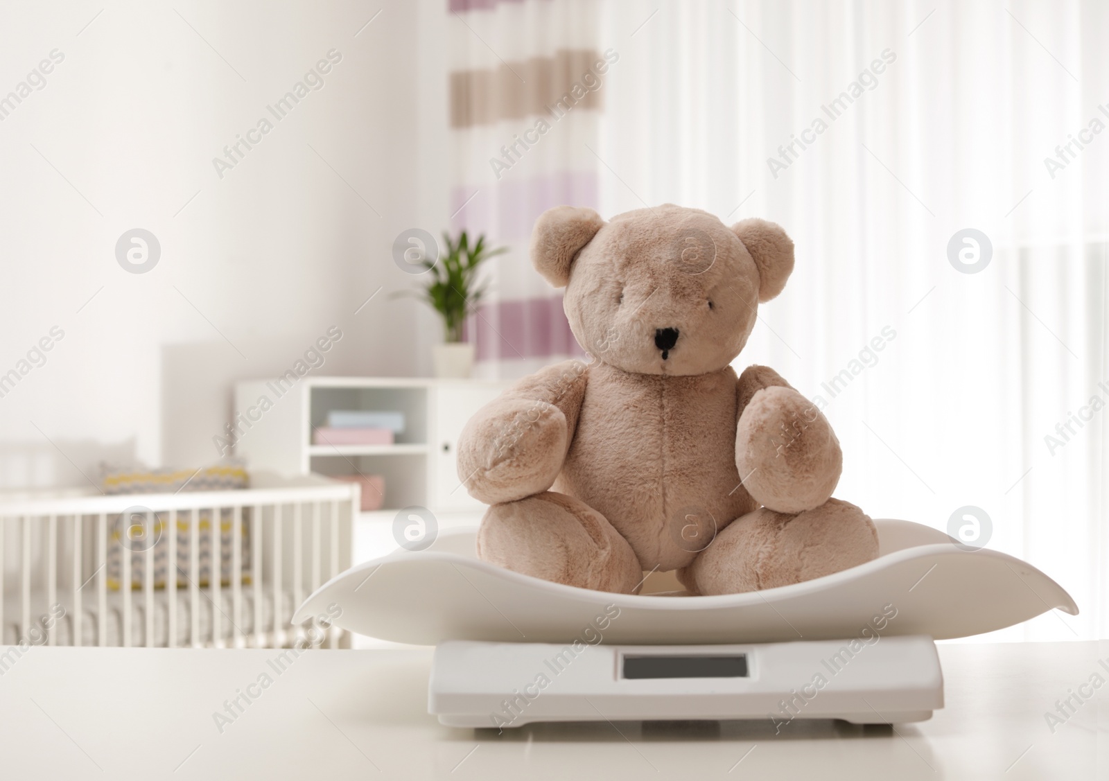 Photo of Baby scales with teddy bear on table indoors, space for text