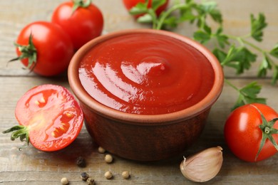 Photo of Tasty ketchup, fresh tomatoes, parsley and spices on wooden table, closeup