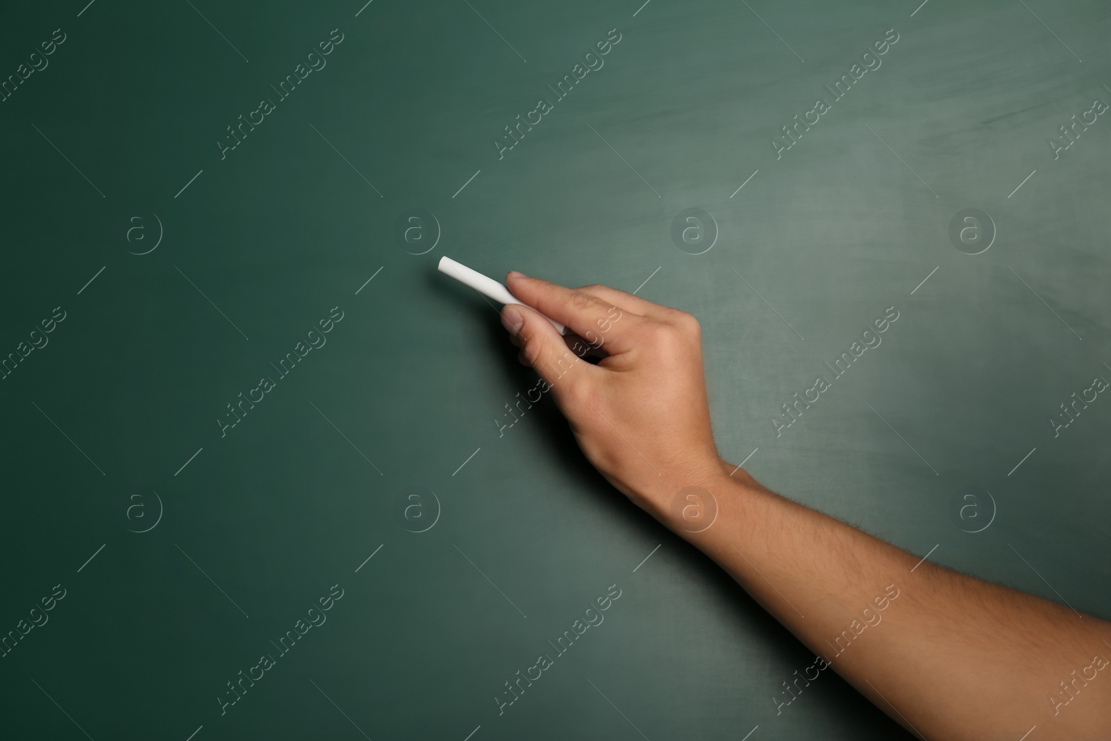 Photo of Man writing with piece of chalk on board