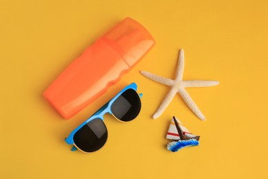 Flat lay composition with bottle of sunscreen on yellow background