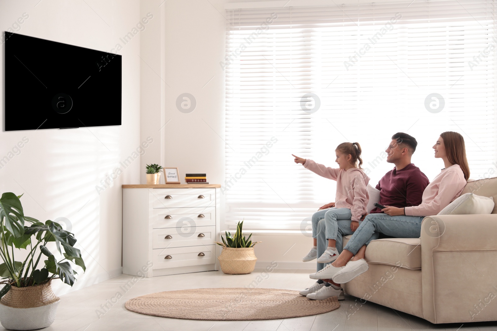 Photo of Happy family watching TV on sofa at home