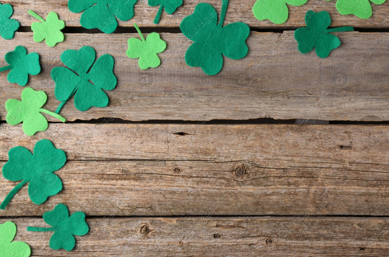 Photo of St. Patrick's day. Decorative clover leaves on wooden background, flat lay. Space for text