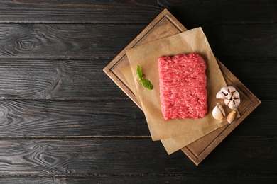 Photo of Fresh raw minced meat on black wooden table, top view. Space for text
