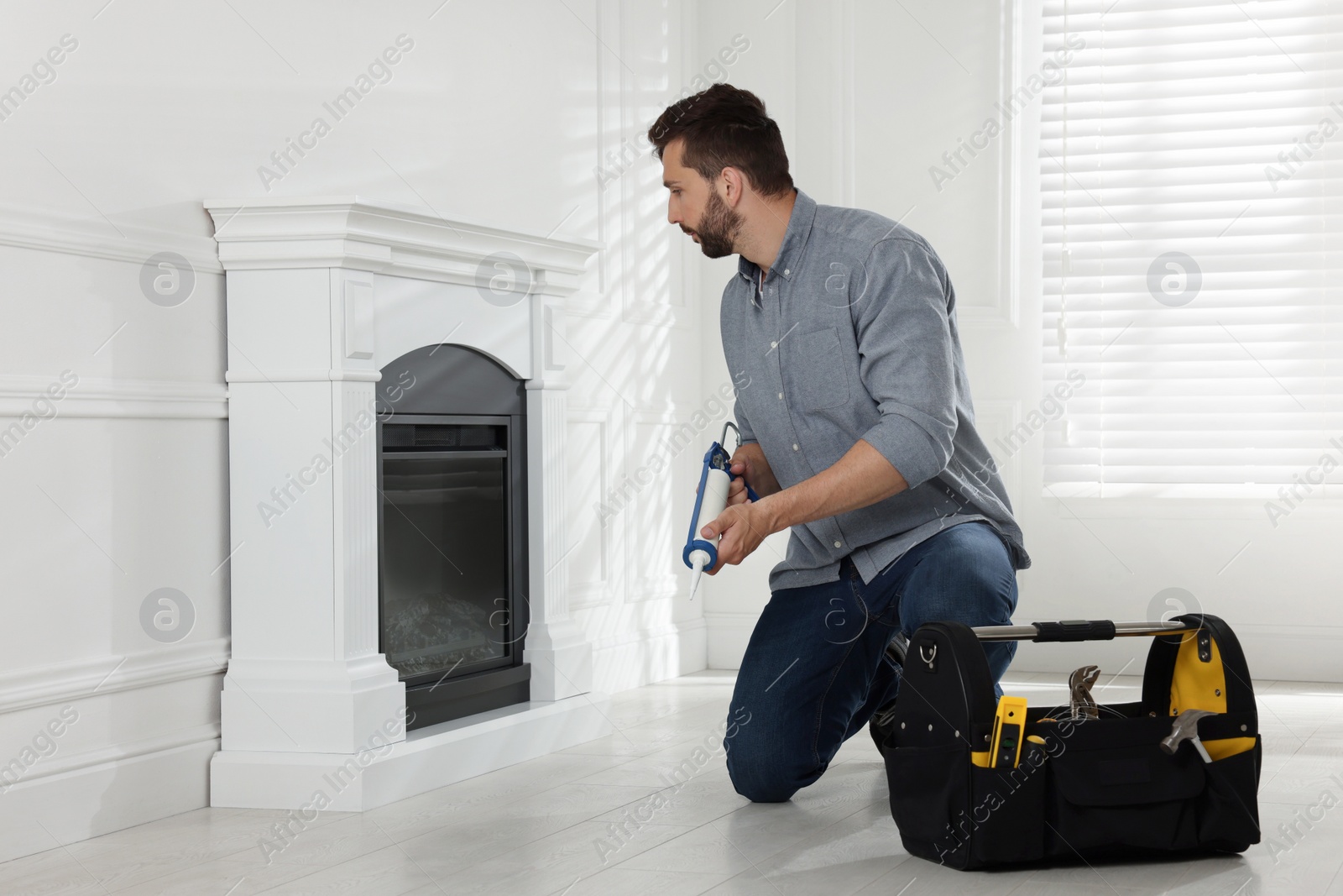 Photo of Man installing electric fireplace near white wall in room