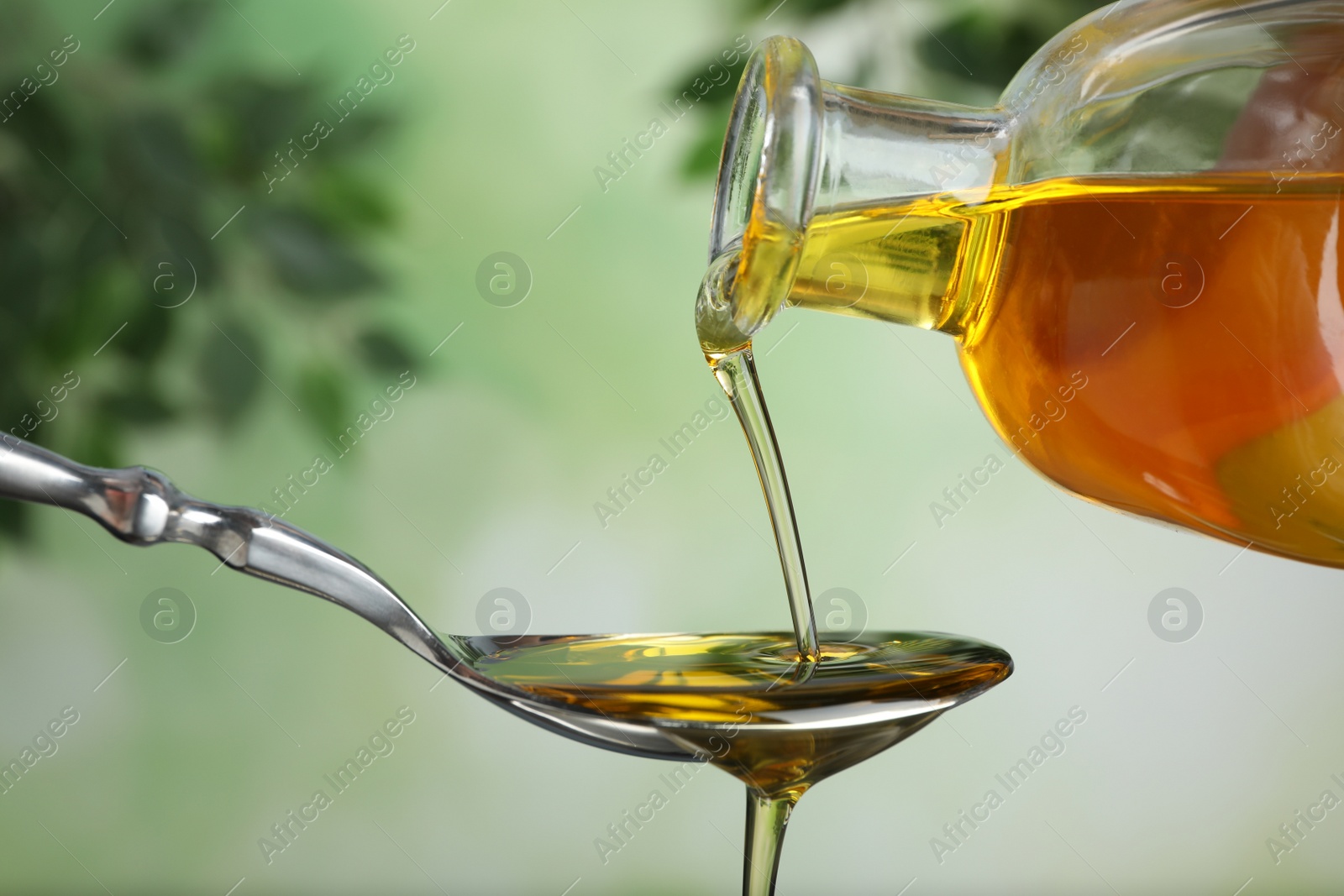 Photo of Pouring hemp oil into spoon on blurred background, closeup