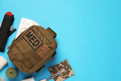 Photo of Military first aid kit and equipment on light blue background, flat lay. Space for text