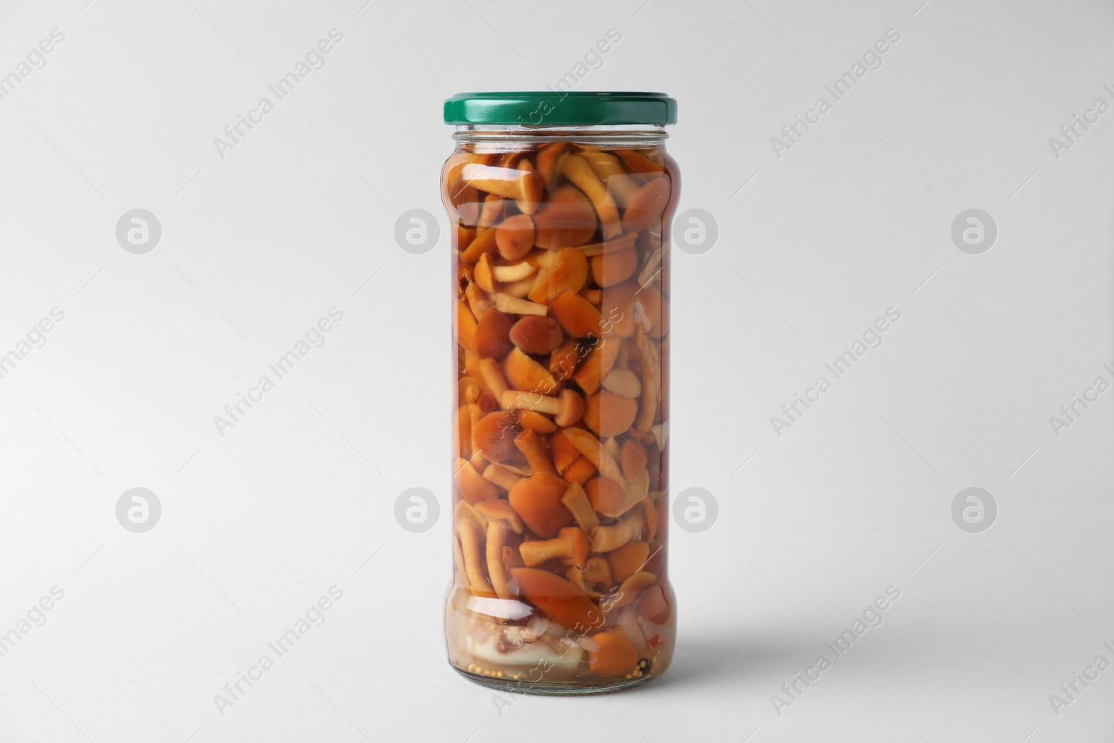 Photo of Jar of pickled mushrooms on light grey background