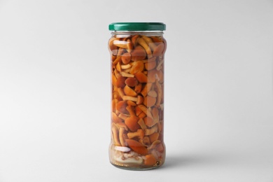 Photo of Jar of pickled mushrooms on light grey background