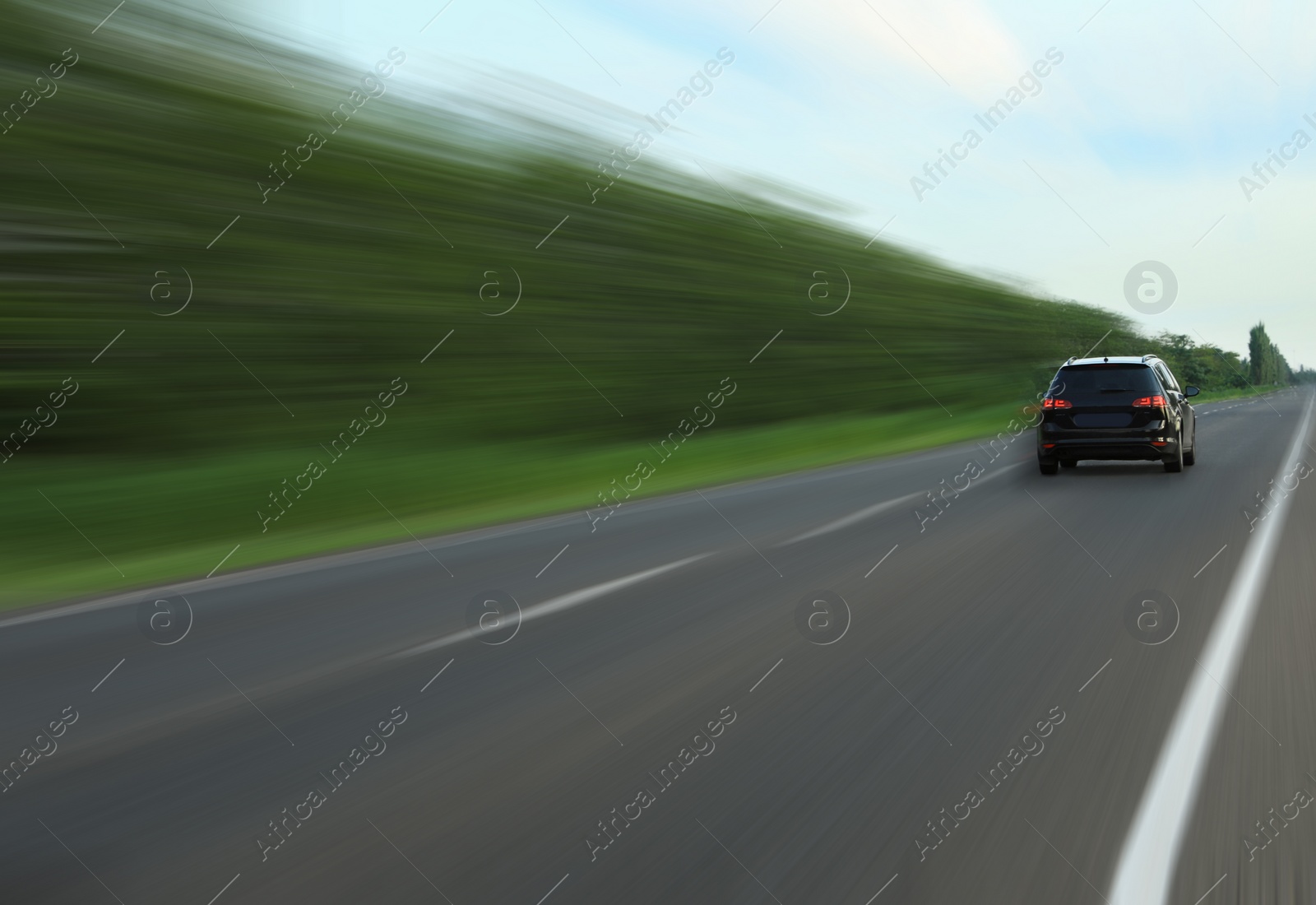 Image of Black car driving at high speed on asphalt road outdoors, motion blur effect