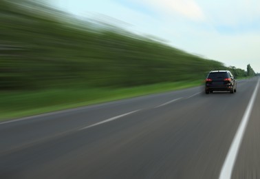 Image of Black car driving at high speed on asphalt road outdoors, motion blur effect