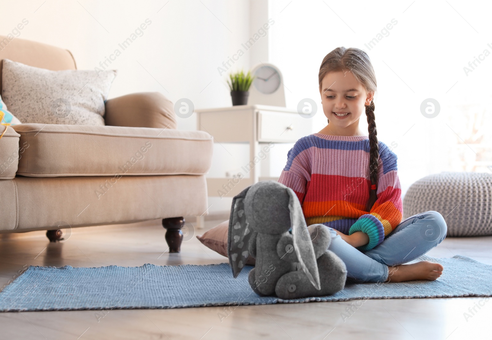 Photo of Cute little child playing with toy bunny on floor indoors. Space for text