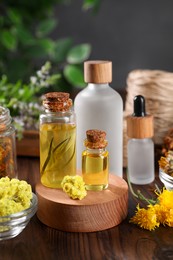 Photo of Bottles of essential oils and different herbs on wooden table