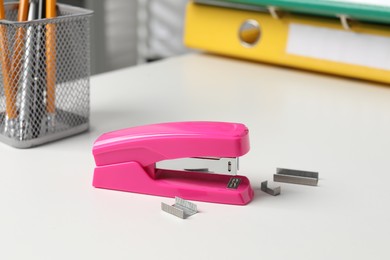 Photo of Stapler and metal staples on white table indoors