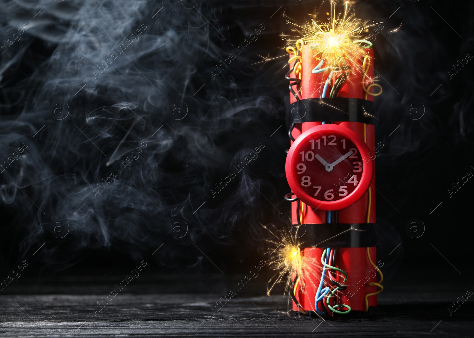 Image of Dynamite time bomb with burning wires on black wooden table, space for text