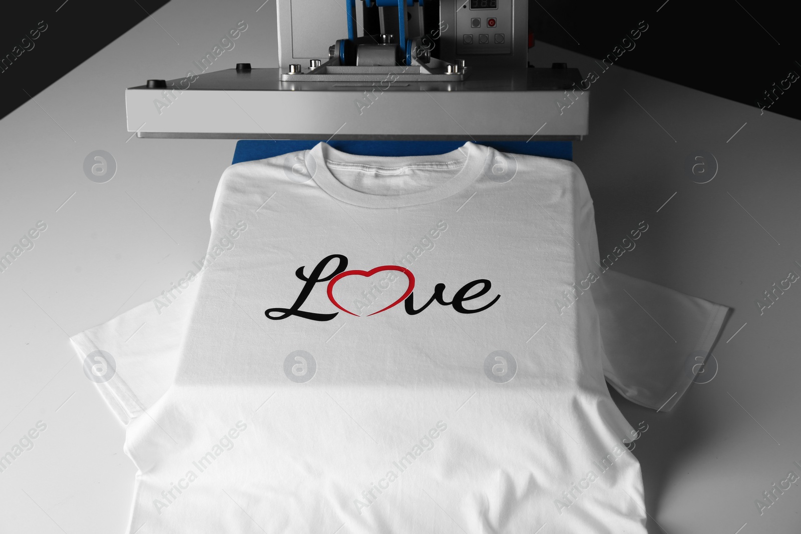 Photo of Printing logo. Heat press with t-shirt on white table