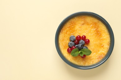 Delicious creme brulee with fresh berries on beige background, top view. Space for text