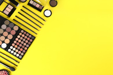 Flat lay composition with makeup brushes on yellow background, space for text