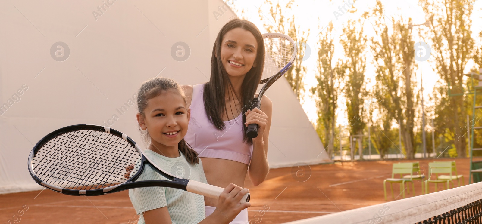 Image of Mother with her daughter on tennis court. Banner design with space for text