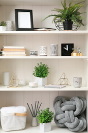 Photo of White shelving unit with plants and different decorative stuff