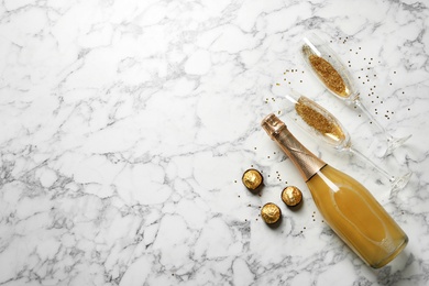 Photo of Flat lay composition with bottle of champagne for celebration on white marble background. Space for text