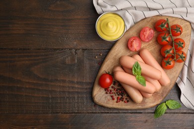 Delicious boiled sausages, sauce, tomatoes and spices on wooden table, flat lay. Space for text