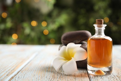 Composition with spa cosmetic and plumeria flower on light wooden table. Space for text